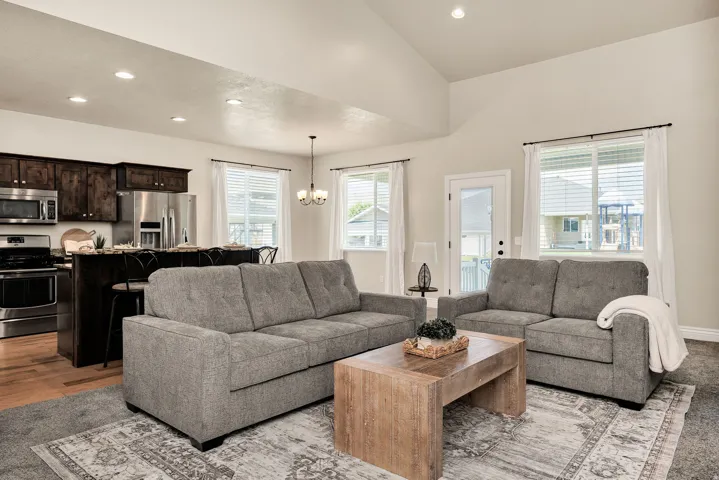 Open-concept living space featuring vaulted ceilings, recessed lighting, and large windows