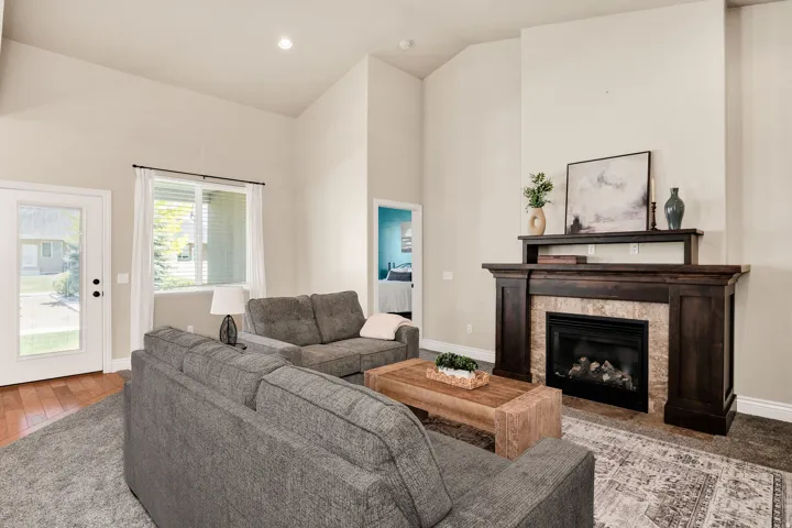 Vaulted ceiling living room featuring a gas fireplace with a dark wood mantel and stone surround