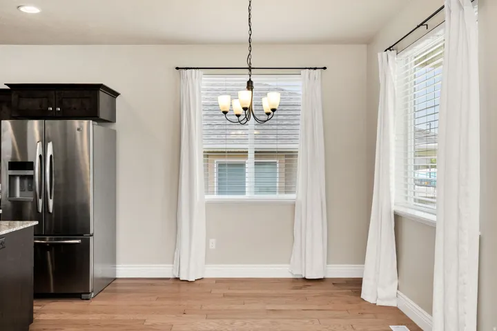 Bright dining space featuring wood-finish flooring, a contemporary chandelier, two windows with blinds, and recessed lighting