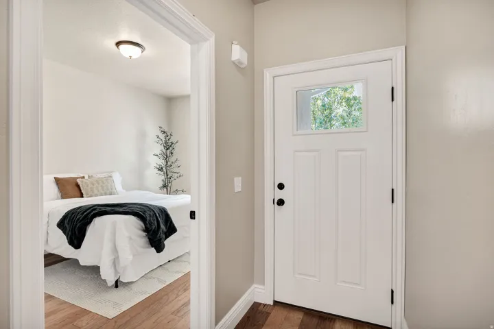 Entry door with upper pane window, black hardware, and wood-finish flooring extending into the room beyond