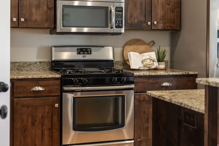 Kitchen featuring stainless steel appliances, dark wood cabinetry, and speckled countertops
