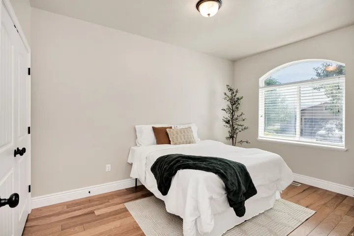 Arched window featuring blinds, wood-finish flooring, white baseboards, and a flush mount ceiling light fixture