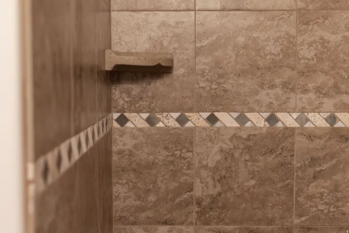 Tiled shower surround featuring a decorative accent band and an integrated soap dish