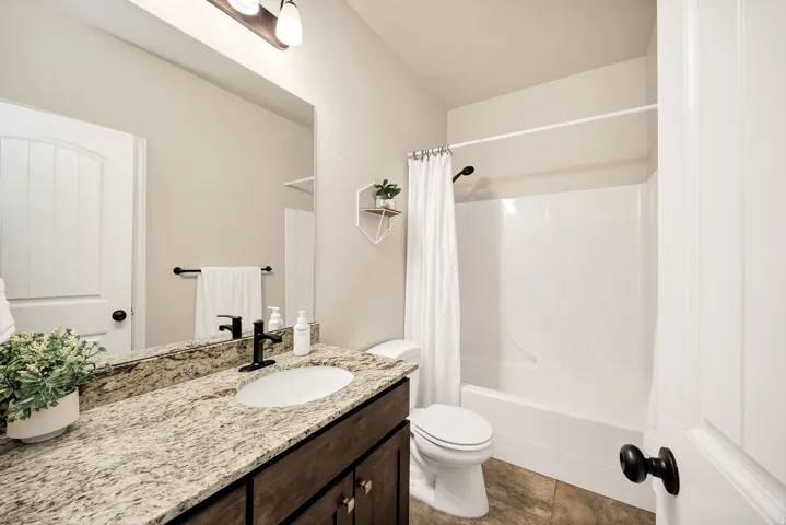 Bathroom featuring a spacious vanity with a light-toned granite countertop and an undermount sink