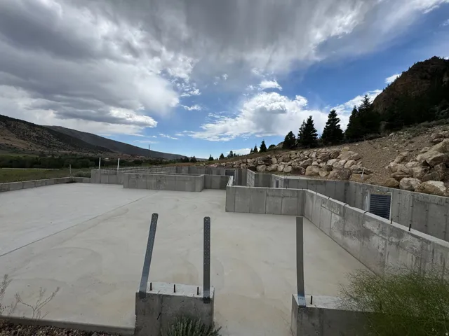 Concrete foundation with multiple sections and integrated rebar, featuring a large level slab