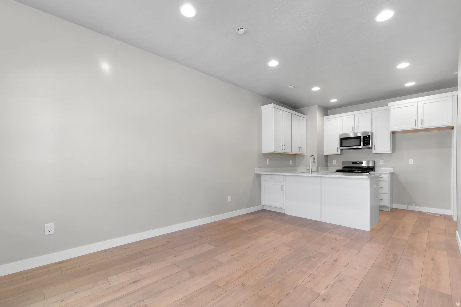 Open-concept kitchen with white cabinetry and stainless steel appliances