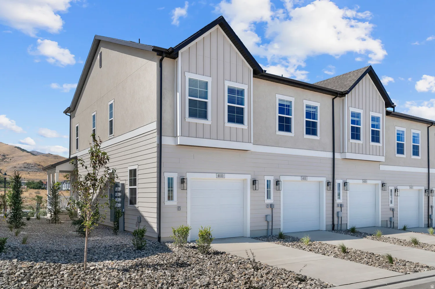 Contemporary townhome exterior featuring an attached garage, vertical and horizontal siding, stucco elements, and outdoor lighting fixtures