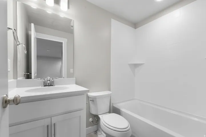 White vanity with a single basin sink, chrome faucet, and rectangular mirror