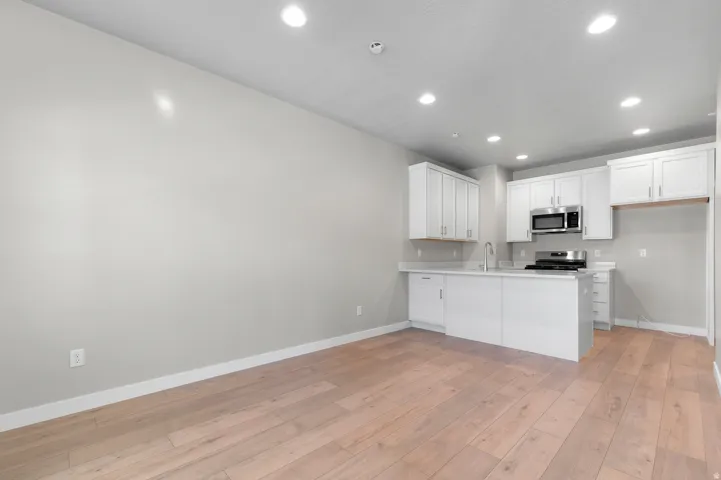 Open-concept kitchen with white cabinetry and stainless steel appliances