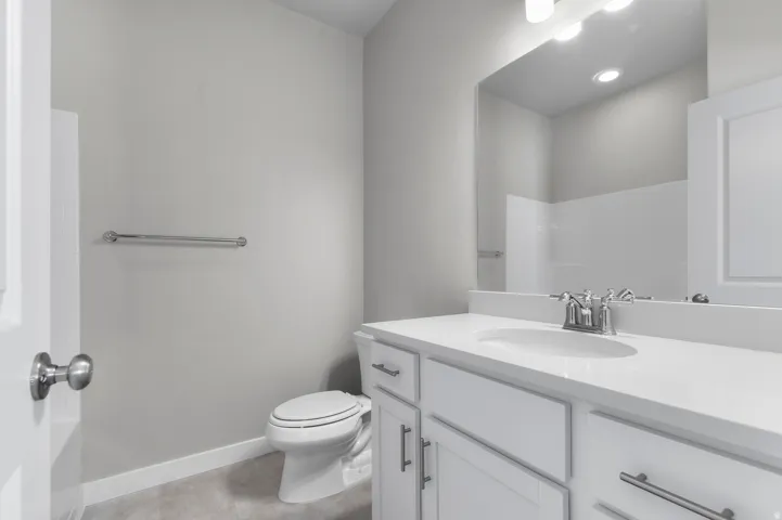 White vanity with shaker-style cabinetry, a white countertop, and an undermount sink with chrome fixtures