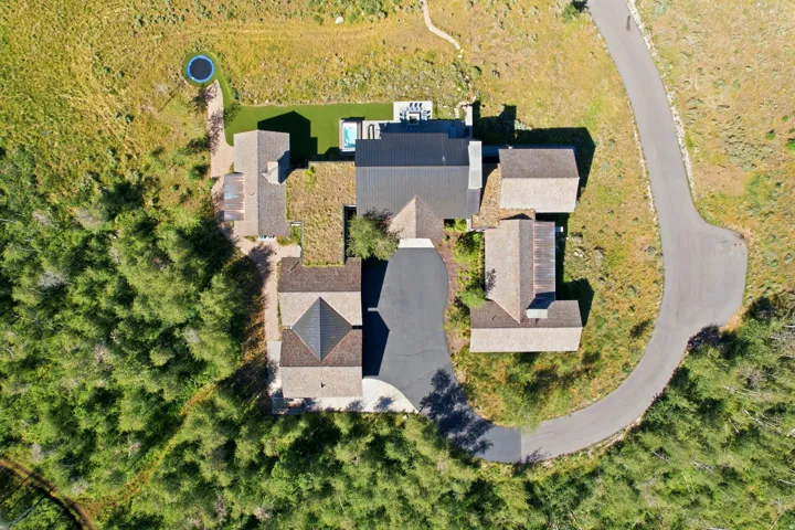 Expansive residential property with multiple structures, asphalt paving, and a swimming pool
