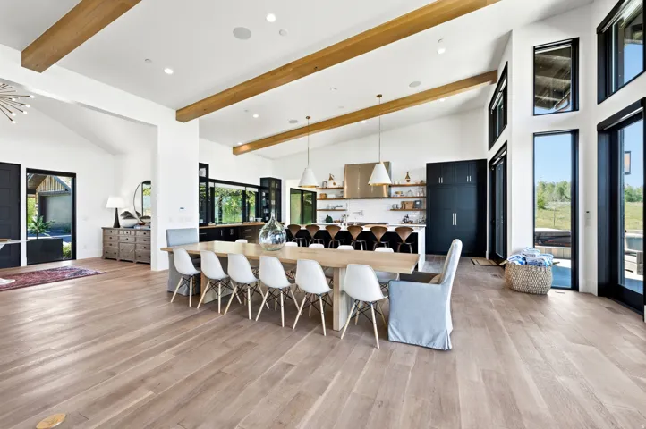 Open-concept living space featuring wood-finish flooring, exposed ceiling beams, and high ceilings