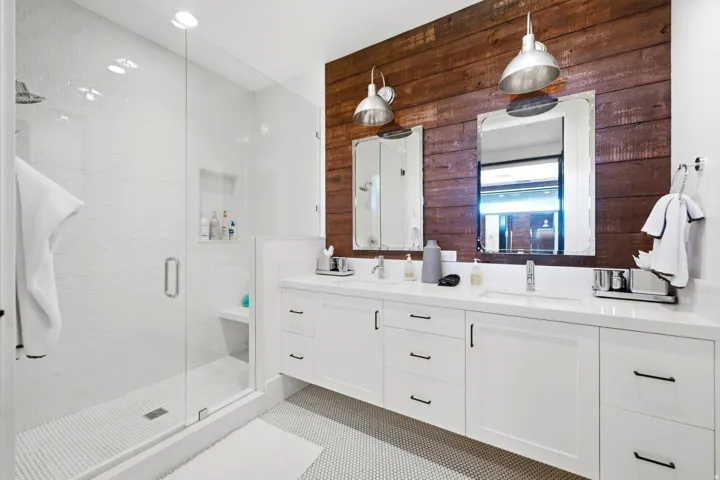 Double vanity with white cabinetry, integrated sinks, and industrial-style pendant lighting