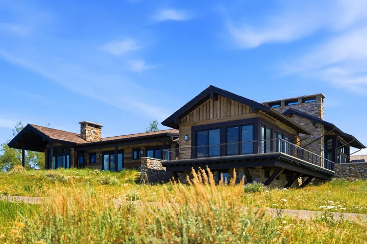 Contemporary ranch-style residence featuring a wood-panel exterior, stone accents, and a low-sloping roofline