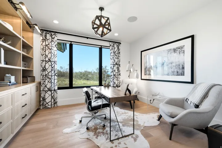 Spacious room featuring light wood-finish flooring, a large window with black trim, and a contemporary geometric light fixture