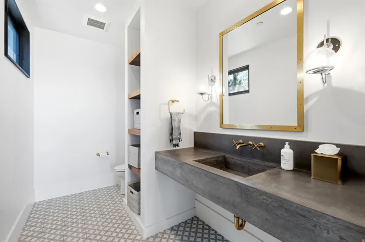 Modern vanity with integrated sink, wall-mounted brass faucet, and gold-framed mirror