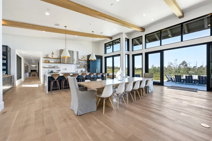 Spacious open-concept living area featuring light wood-finish flooring and exposed wood beams