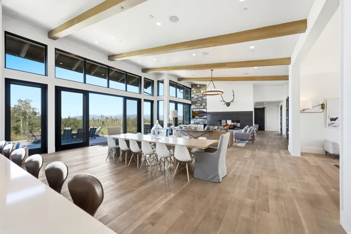 Expansive open-concept interior featuring wood-finish flooring, exposed ceiling beams, a stone accent wall, and a fireplace with a black hearth