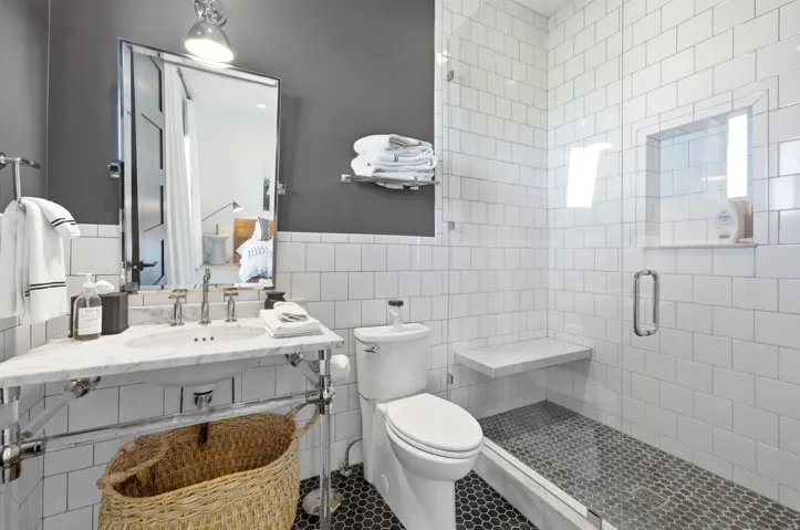 Bathroom featuring a glass-enclosed shower with white subway tile, a built-in shower niche, and a stone bench