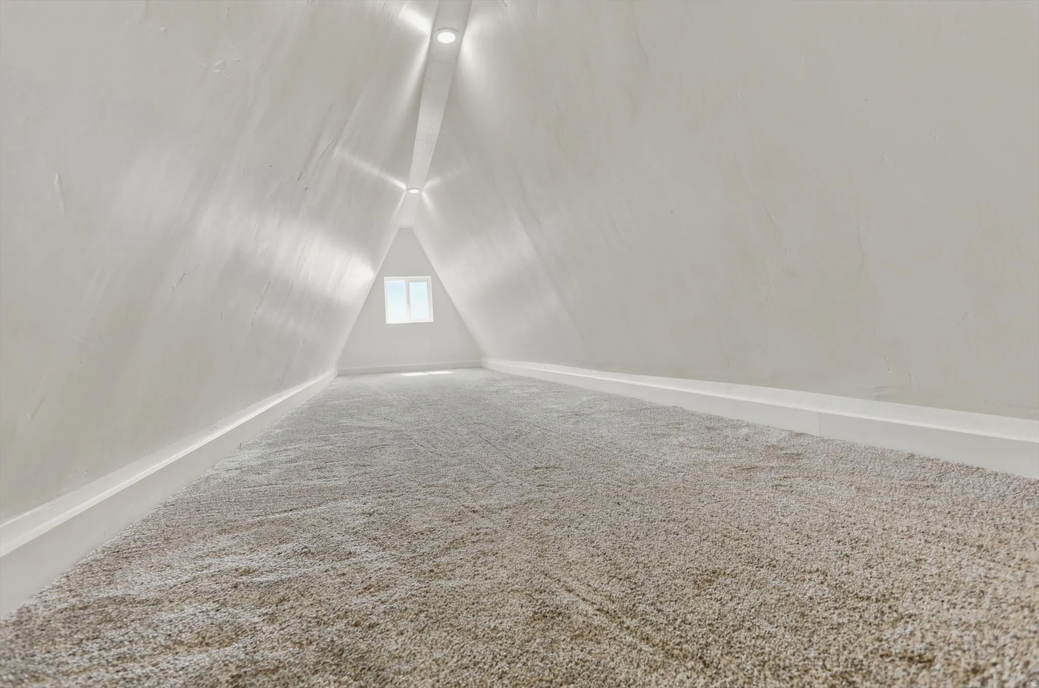 A-frame attic space featuring plush carpeting and a triangular window