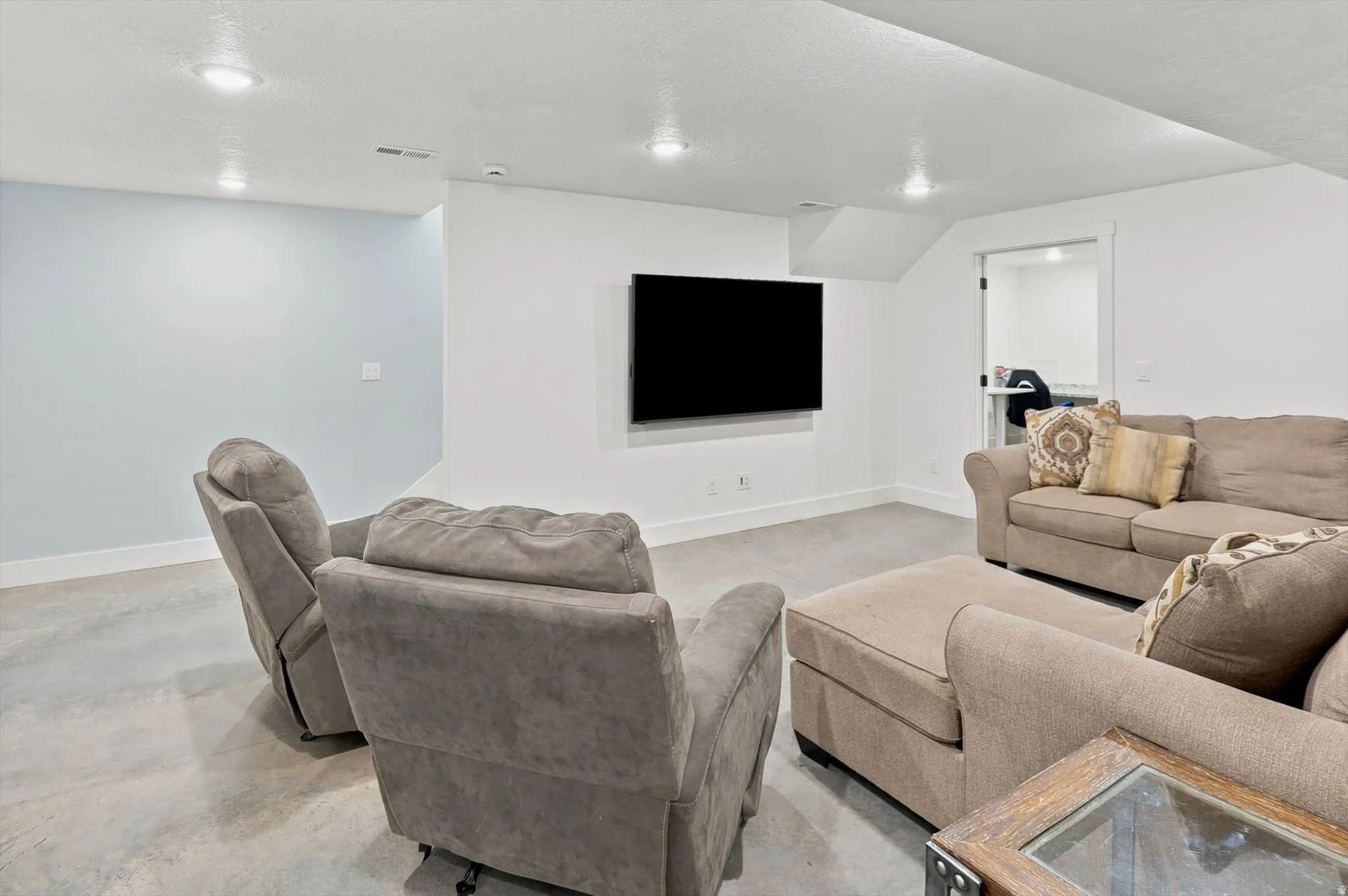 Recreation room featuring recessed lighting, a wall-mounted display area, light blue accent wall, and concrete flooring