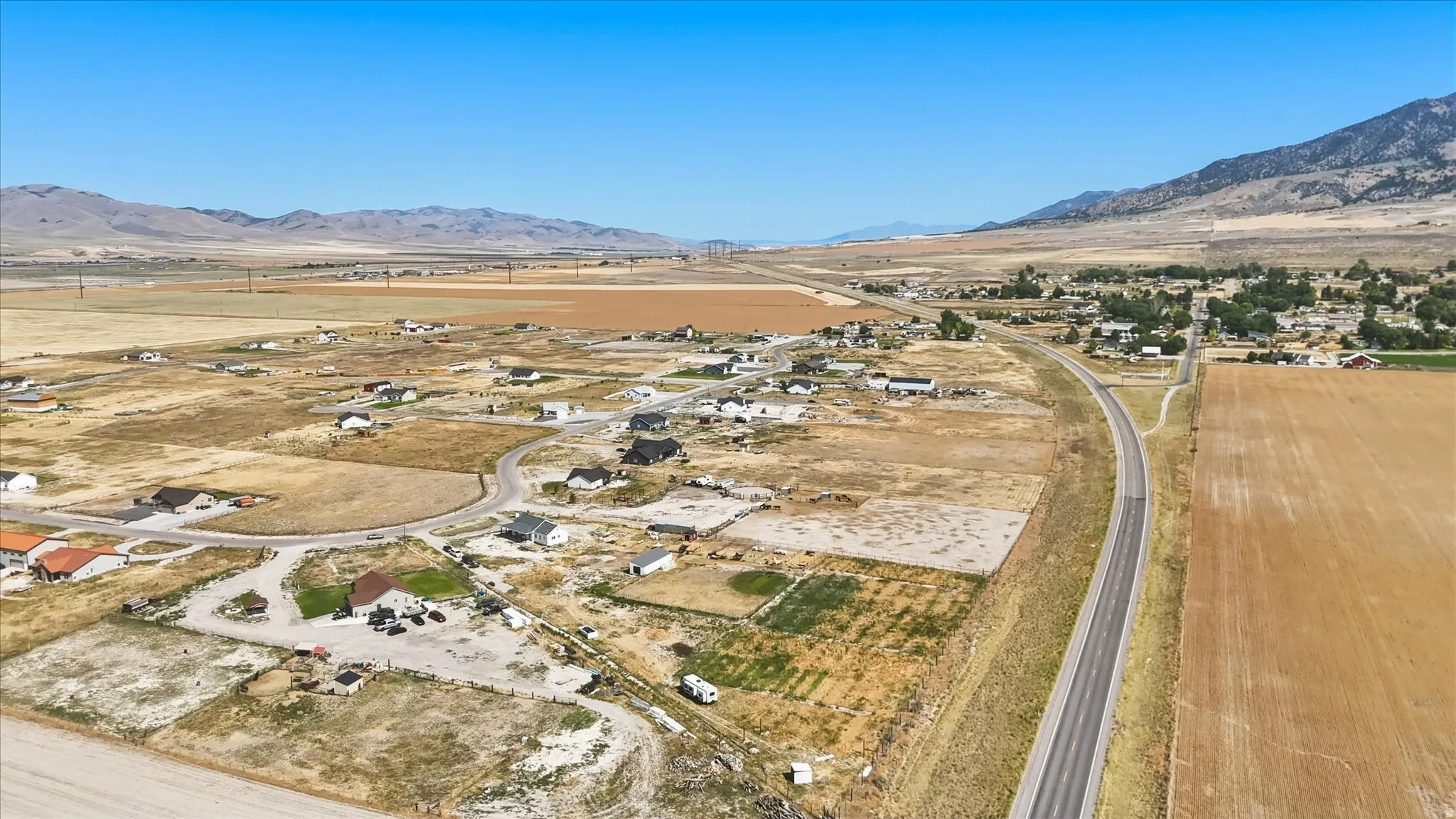 Rural landscape featuring expansive fields and distant mountains under a clear sky