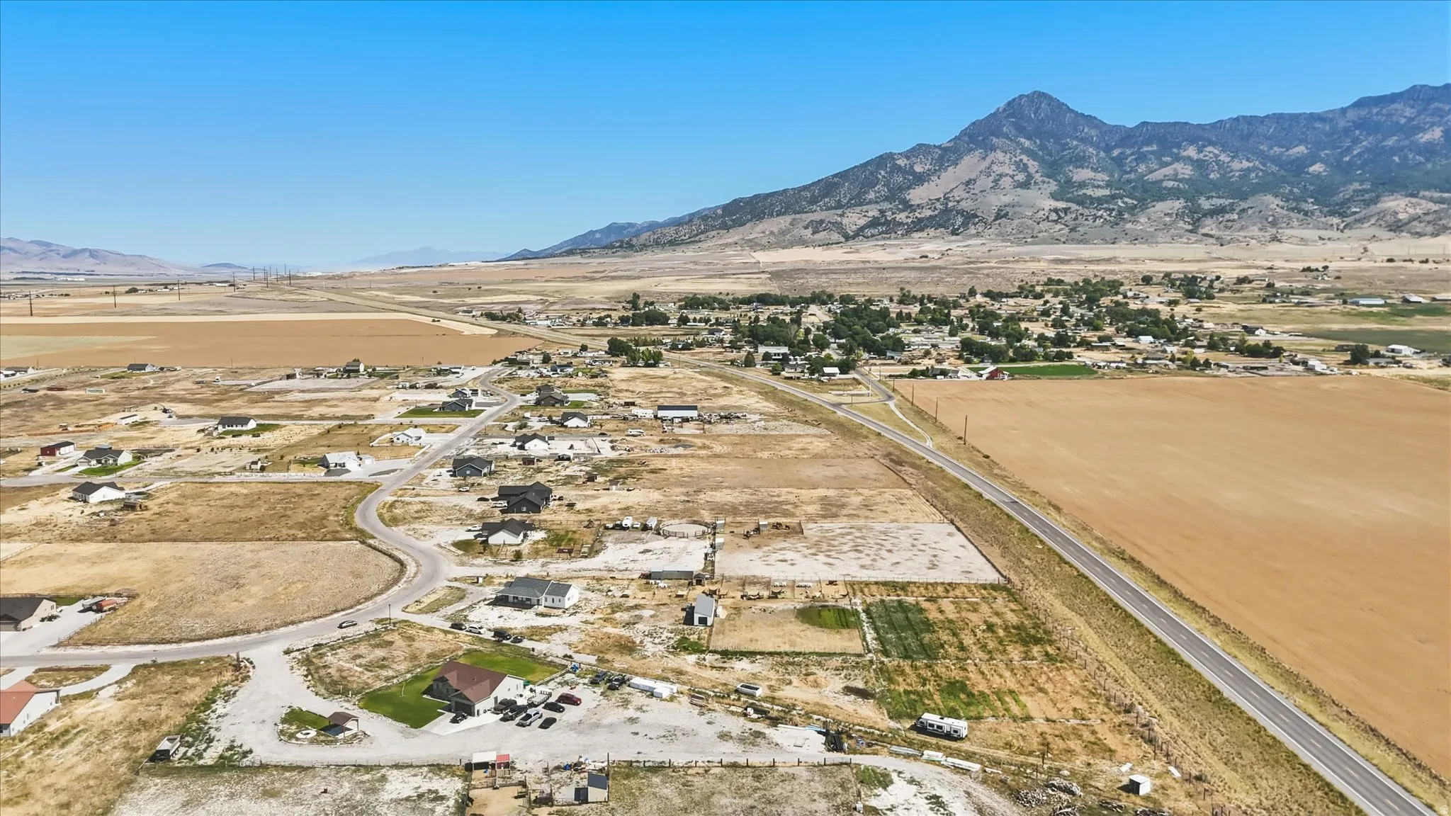 Expansive rural landscape with scattered residential properties, a winding road, and agricultural fields