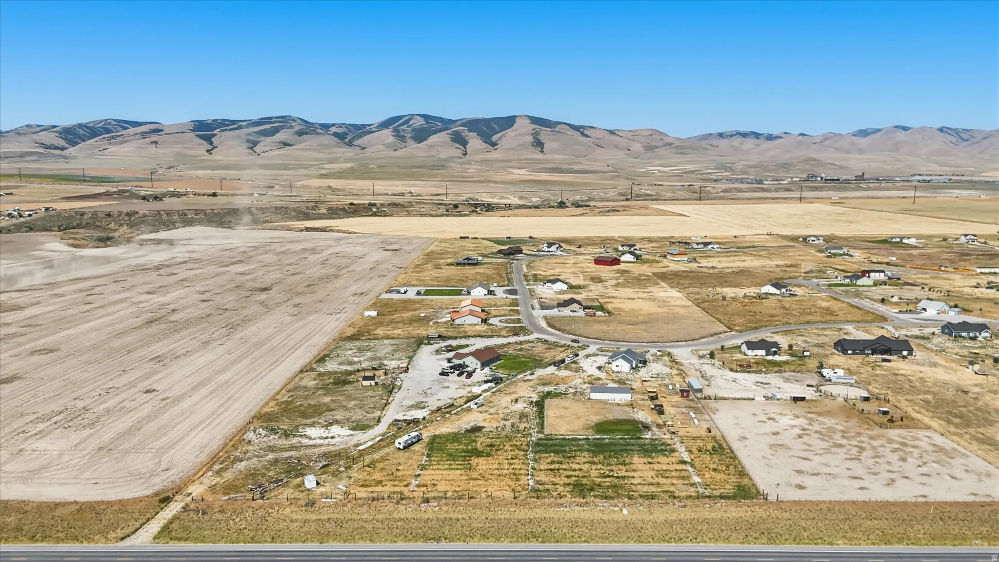 Expansive undeveloped land featuring a cleared section, surrounding rural properties, and distant mountain ranges