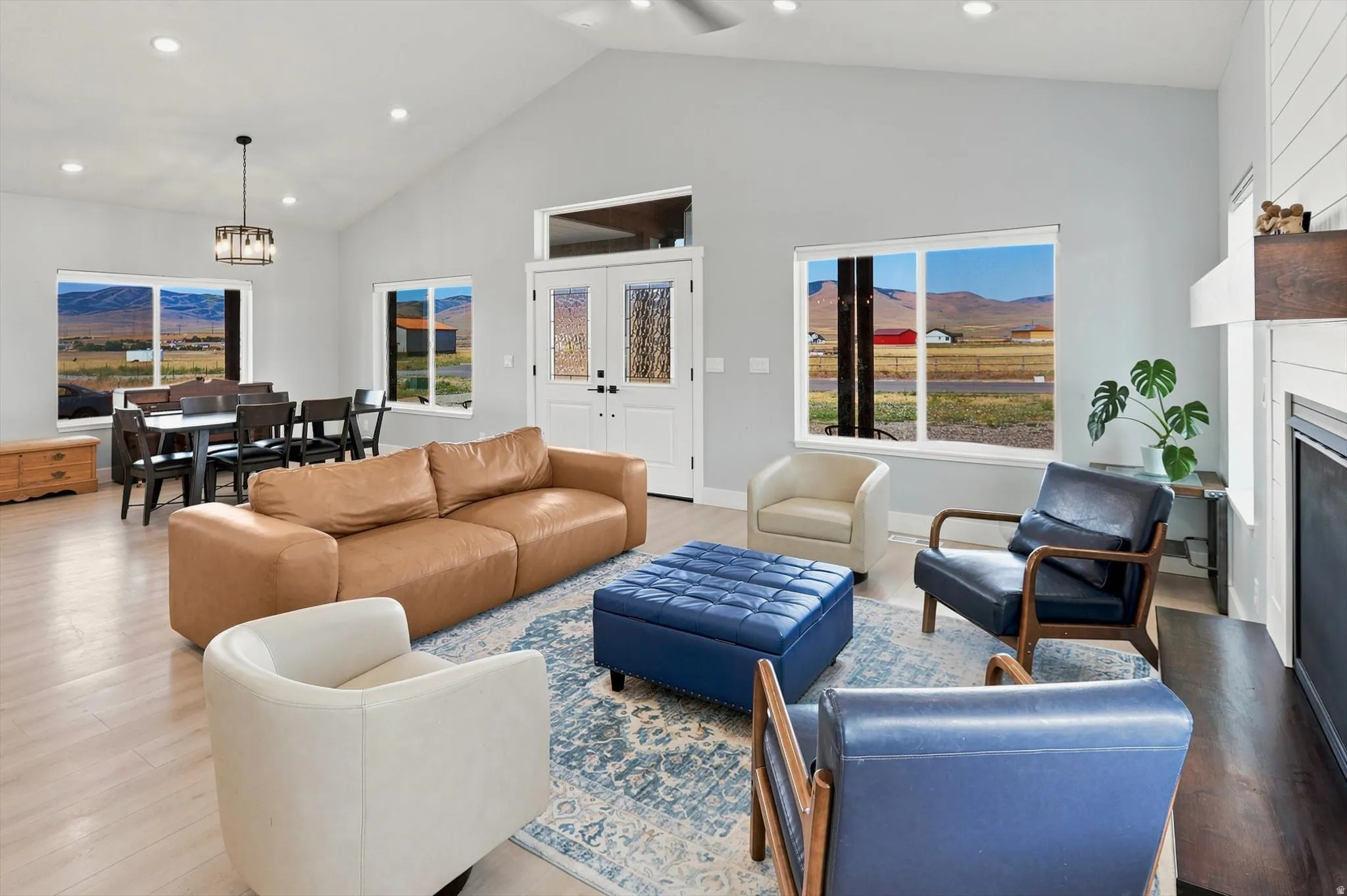 Vaulted ceilings highlight this open-concept living space, featuring wood-finish flooring, a contemporary fireplace with a shiplap surround, and recessed lighting