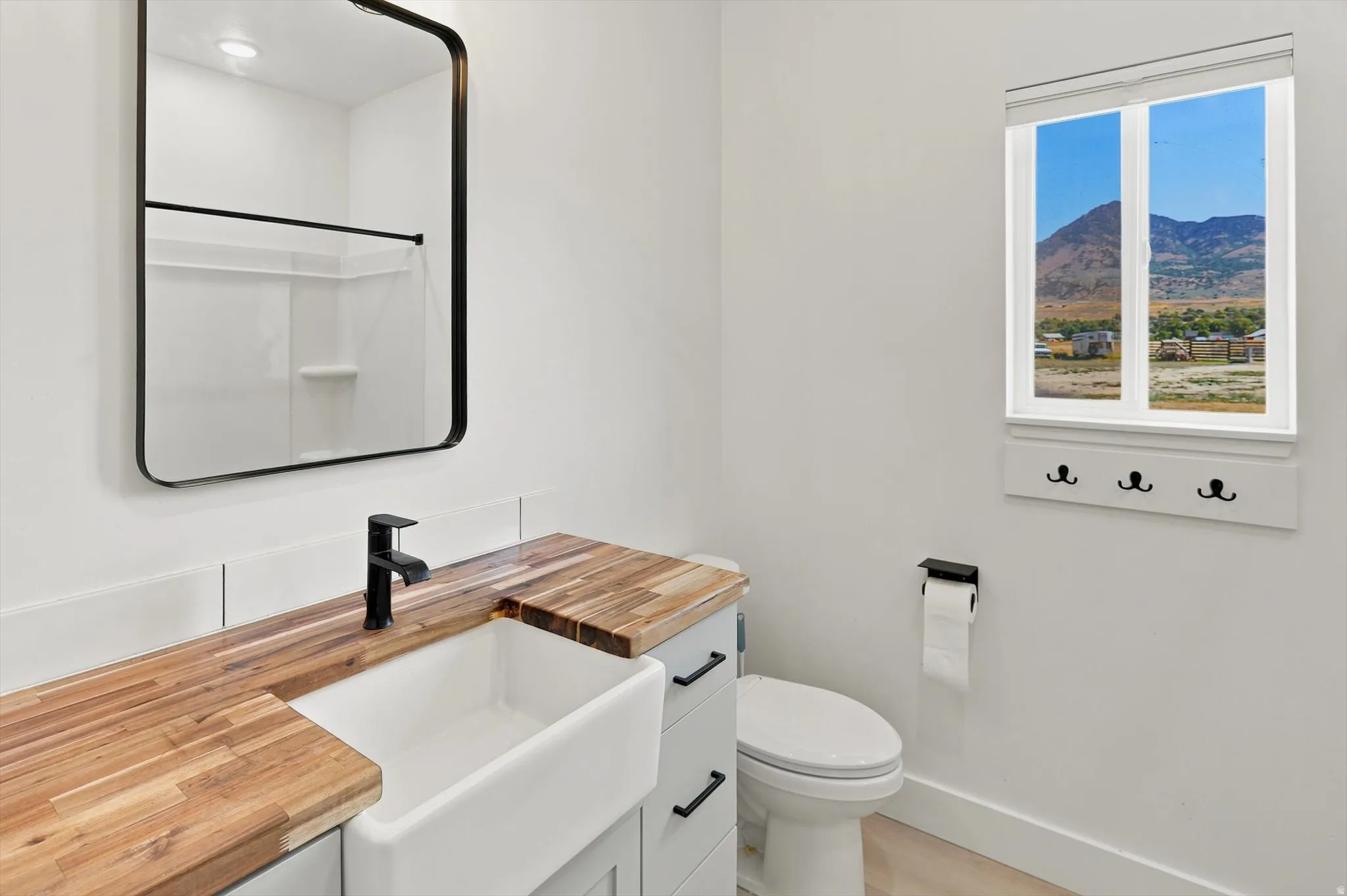 Bathroom featuring a wood-finish countertop, undermount farm sink, and matte black faucet