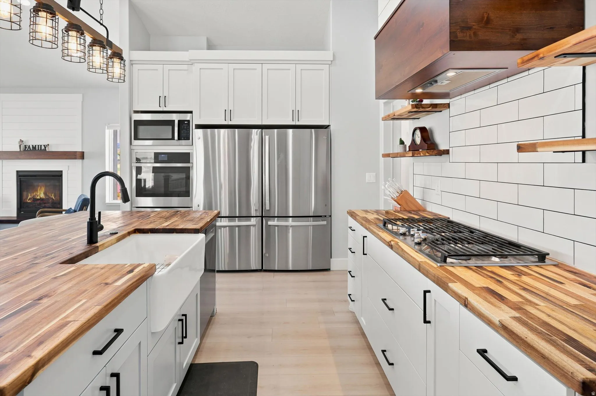 Gourmet kitchen featuring butcher block countertops, white shaker cabinetry, stainless steel appliances, a farmhouse sink, and a gas cooktop