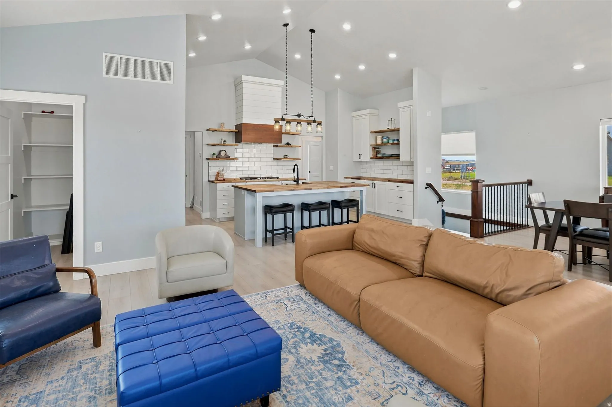 Open-concept living space featuring a vaulted ceiling and light wood-finish flooring