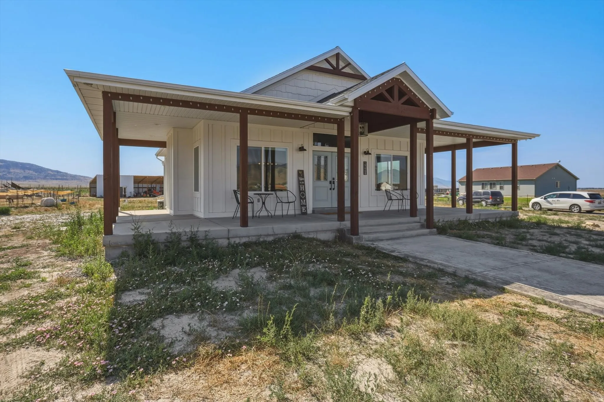White board and batten exterior featuring a covered front porch with dark wood posts and exposed rafter tails
