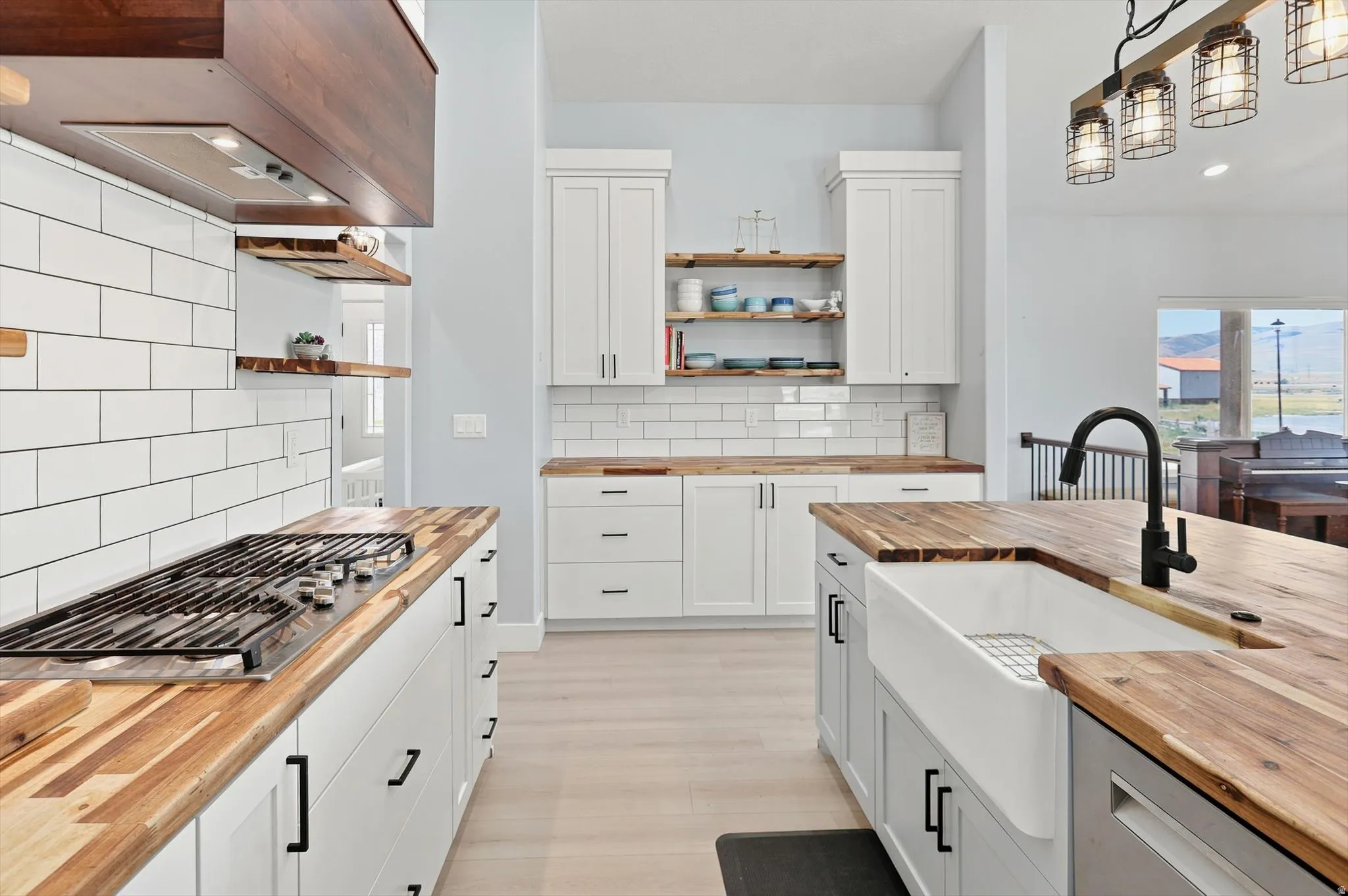 Kitchen featuring butcher block countertops, white shaker cabinetry, white subway tile backsplash, and a farmhouse sink with a matte black faucet