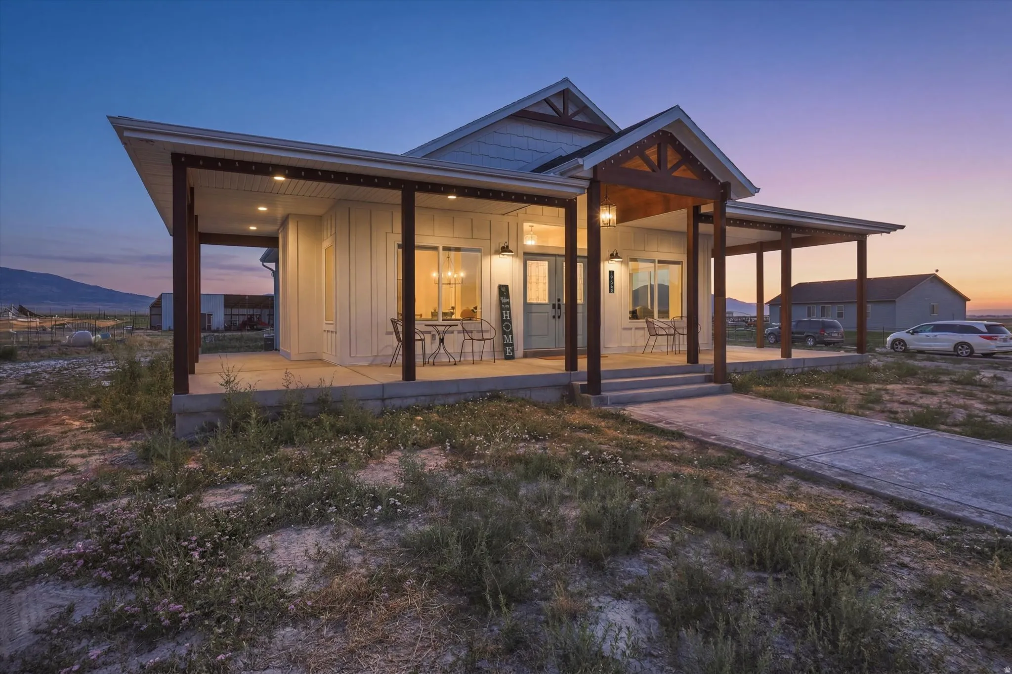Farmhouse-style residence featuring a prominent covered porch with substantial wood columns and exposed rafter tails