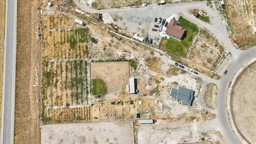 Aerial view of a property featuring two distinct residential structures, agricultural plots, and multiple outbuildings