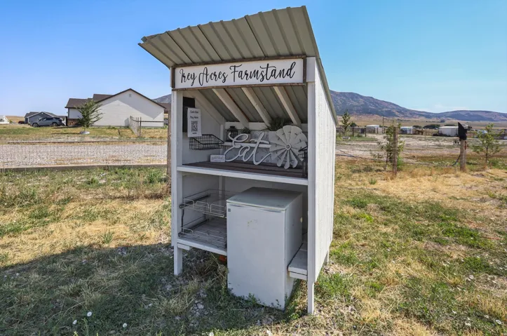 Freestanding white structure with a corrugated metal roof and a "Hey Acres Farmstand" sign