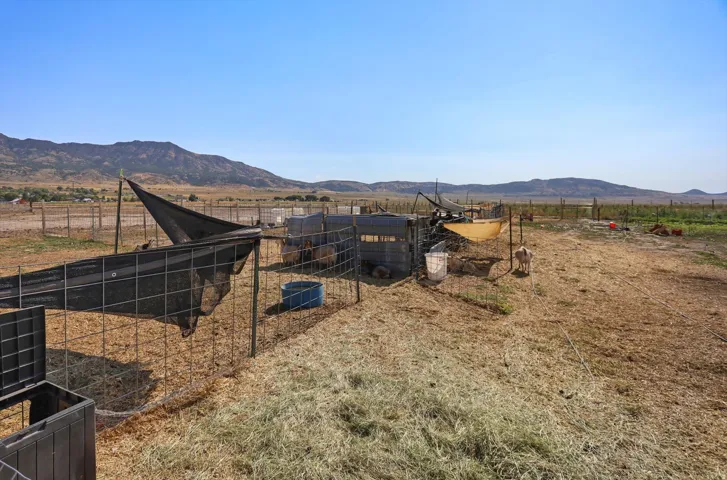 Expansive open land featuring fencing, a shade structure, and distant mountain scenery