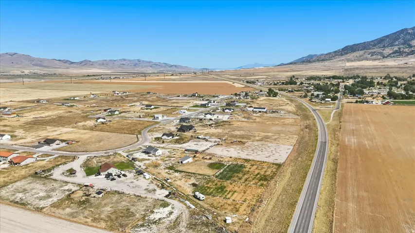 Rural landscape featuring expansive fields and distant mountains under a clear sky