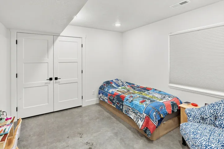 Bright interior space featuring a window with cellular shades, a recessed light, and concrete flooring