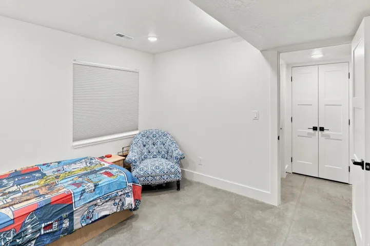 Interior room featuring white walls, contemporary white trim, a recessed window with blinds, and durable concrete flooring