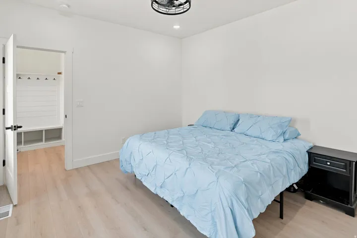 Bright interior space featuring light wood-finish flooring, white walls, and a contemporary ceiling fan