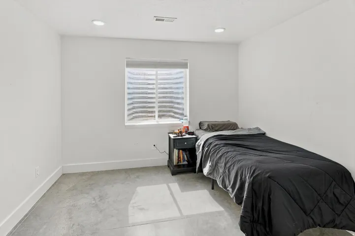 Bright room featuring a window with integrated blinds, recessed lighting, and a concrete floor