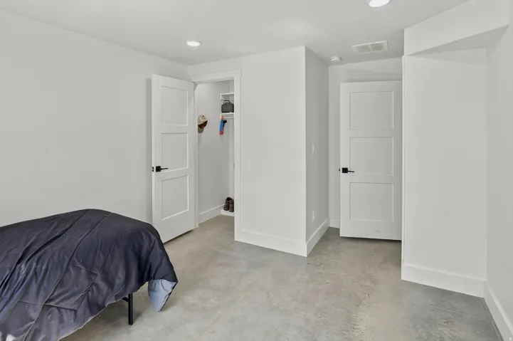 Bright room featuring a three-panel interior door, recessed lighting, and durable concrete flooring