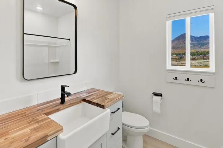 Bathroom featuring a wood-finish countertop, undermount farm sink, and matte black faucet