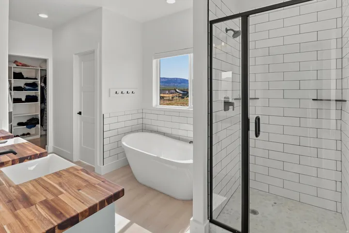 Shower enclosure with black frame, subway tile surround, and pebble-style flooring
