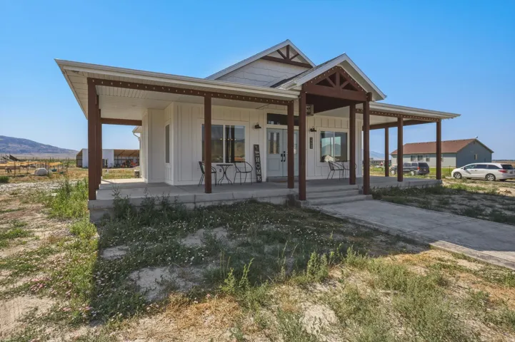 White board and batten exterior featuring a covered front porch with dark wood posts and exposed rafter tails