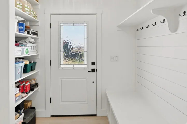 Entryway featuring a white paneled door with decorative glass, built-in shelving, white shiplap wall paneling, and integrated bench seating with storage