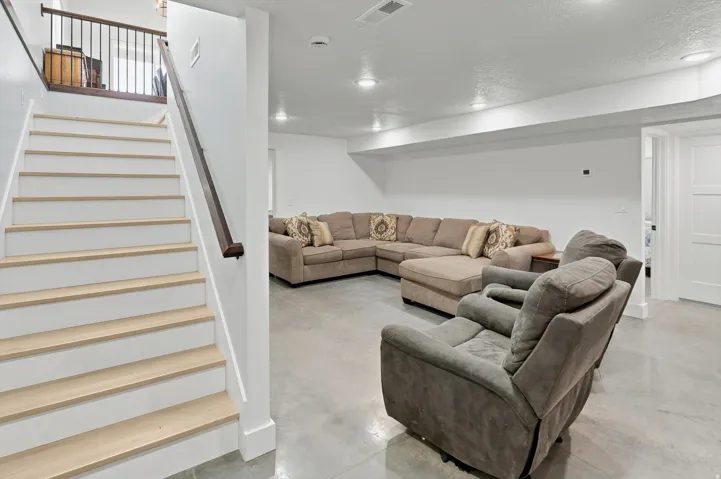Finished basement with recessed lighting, light-colored concrete flooring, and a white paneled door