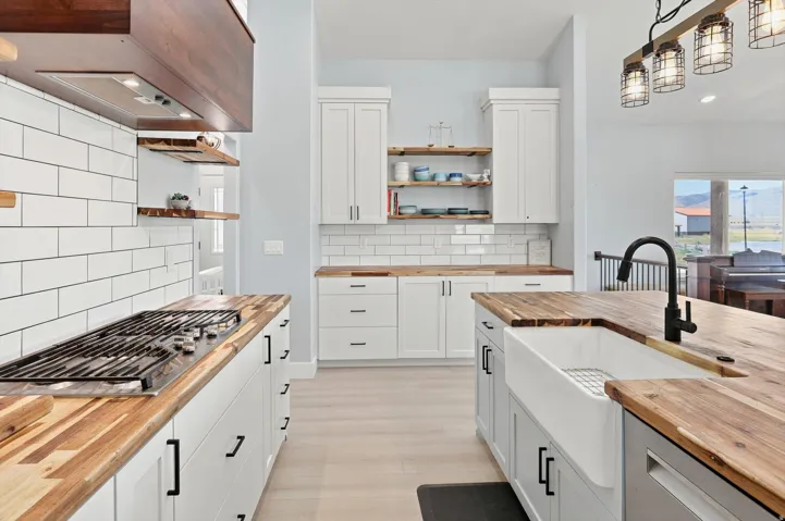 Kitchen featuring butcher block countertops, white shaker cabinetry, white subway tile backsplash, and a farmhouse sink with a matte black faucet